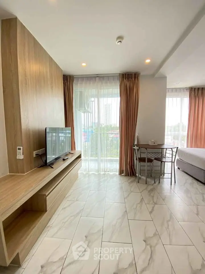 Modern studio apartment with large windows and balcony view, featuring sleek furniture and stylish decor.