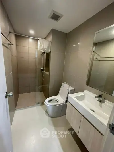 Modern bathroom with sleek fixtures and spacious shower in contemporary apartment.