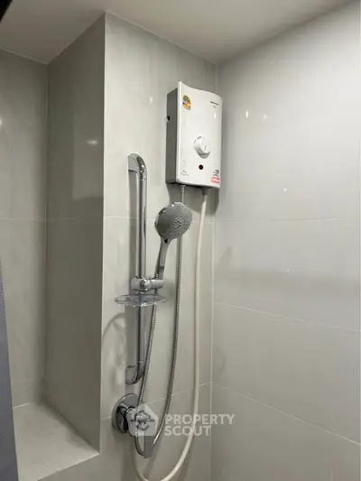 Modern bathroom with sleek shower and water heater in a contemporary apartment.