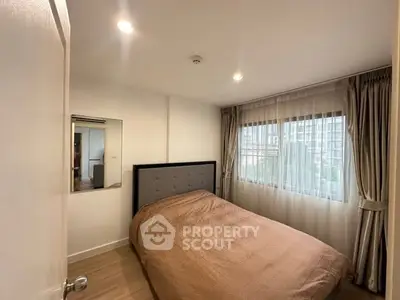 Cozy bedroom with large window and modern decor in a stylish apartment.