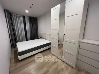 Modern minimalist bedroom with sleek white furniture and large window for natural light.