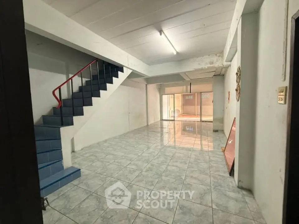 Spacious open-plan interior with tiled flooring and staircase, ideal for customization.