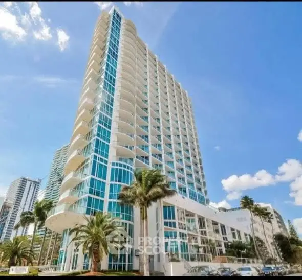 Stunning modern high-rise building with glass facade and palm trees, offering luxurious urban living.