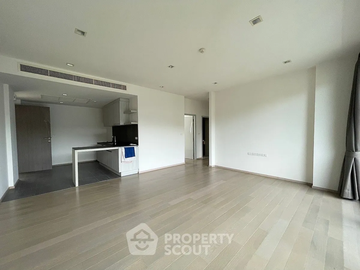 Spacious open-plan living area with modern kitchen, ample natural light, and sleek wooden flooring, ideal for entertaining and comfortable living.