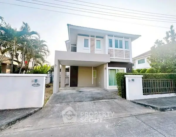 Modern two-story house with driveway and lush greenery in a serene neighborhood.