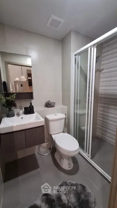 Modern bathroom with glass shower and sleek fixtures in stylish apartment.