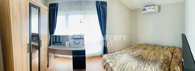 Cozy bedroom with modern wardrobe and air conditioning, featuring ample natural light.