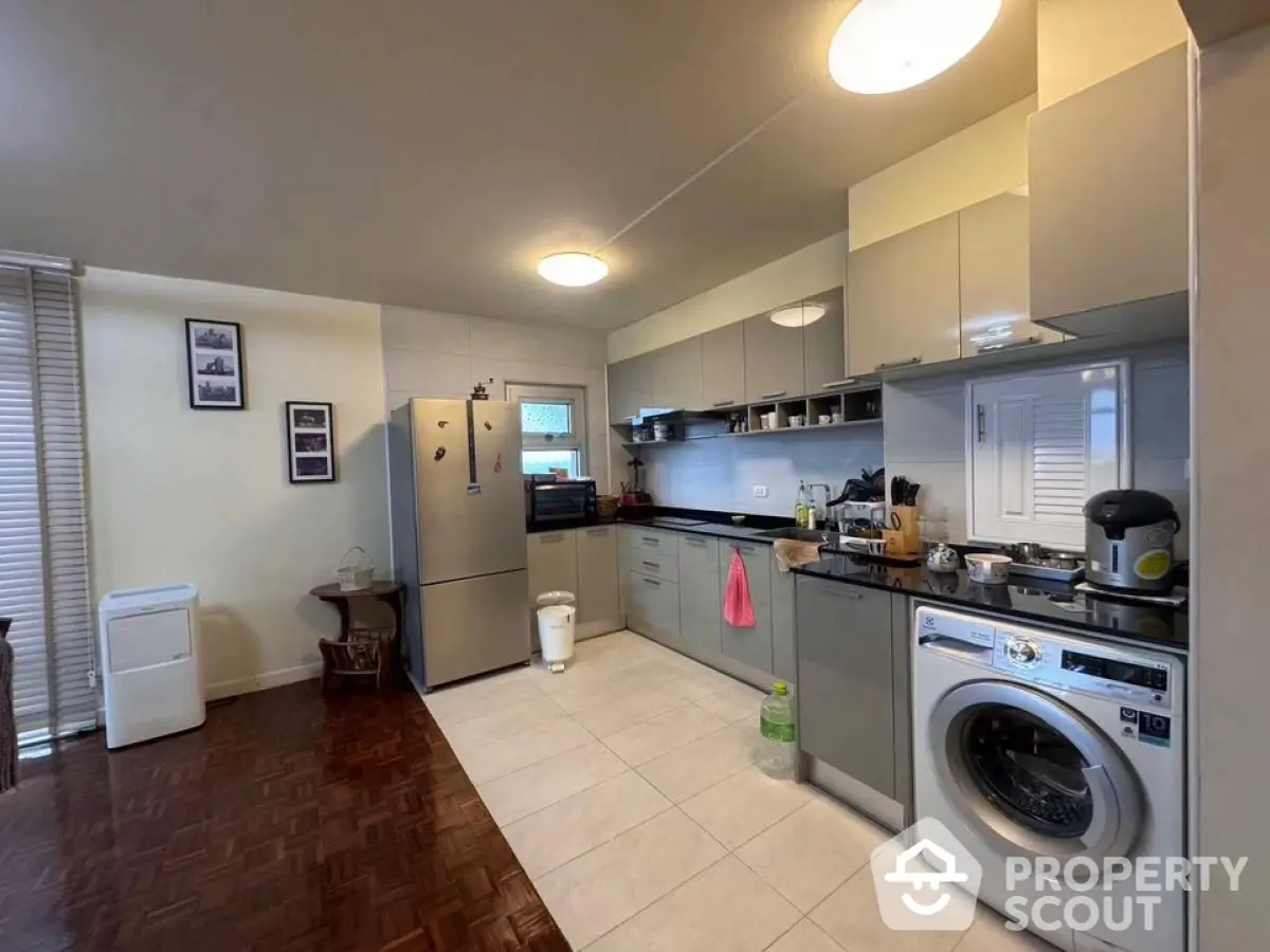 Modern kitchen with washing machine and stainless steel appliances in open layout design.