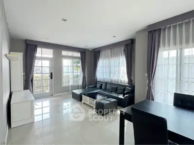 Spacious modern living room with sleek black leather sofa and elegant curtains