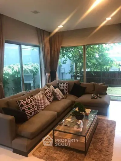 Spacious living room with modern decor and large windows overlooking a garden.