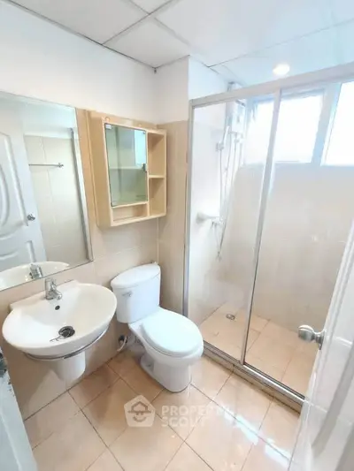 Modern bathroom with glass shower and sleek fixtures in a bright, tiled space.