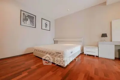 Spacious bedroom with wooden flooring and modern decor in a stylish apartment.