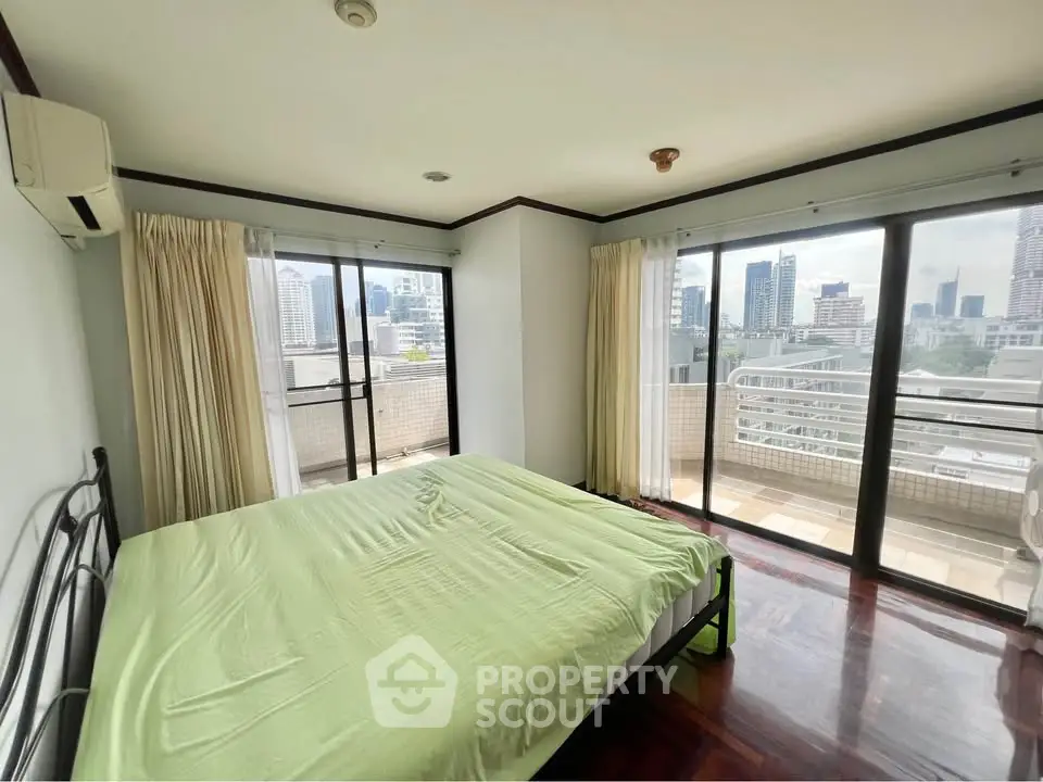 Spacious bedroom with city view and balcony access in modern apartment