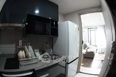 Modern compact kitchen with sleek appliances and open view to cozy living room.