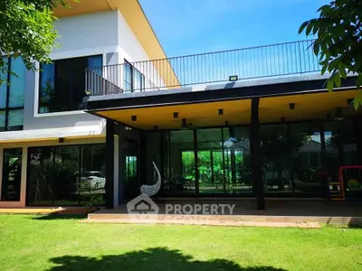 Modern home with expansive glass windows and lush green lawn