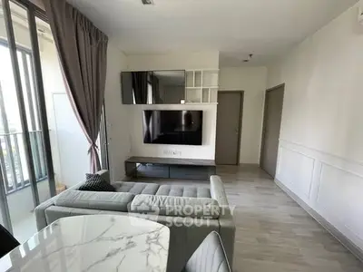 Modern living room with sleek furniture and large TV, featuring elegant curtains and natural light.