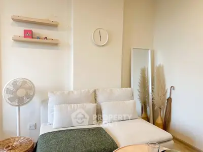 Cozy living room with modern decor, featuring a comfortable sofa, wall clock, and stylish shelves.