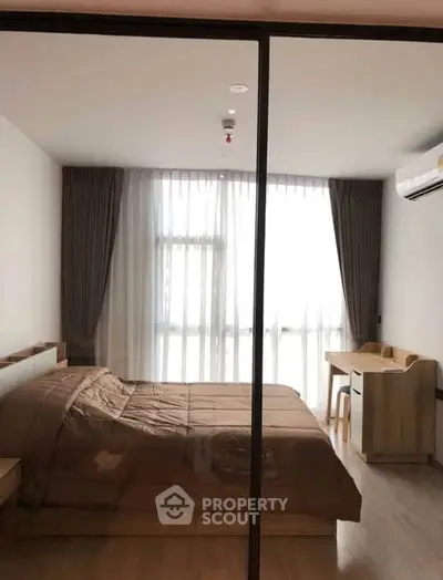 Modern bedroom with large window, wooden furniture, and neutral decor in a stylish apartment.