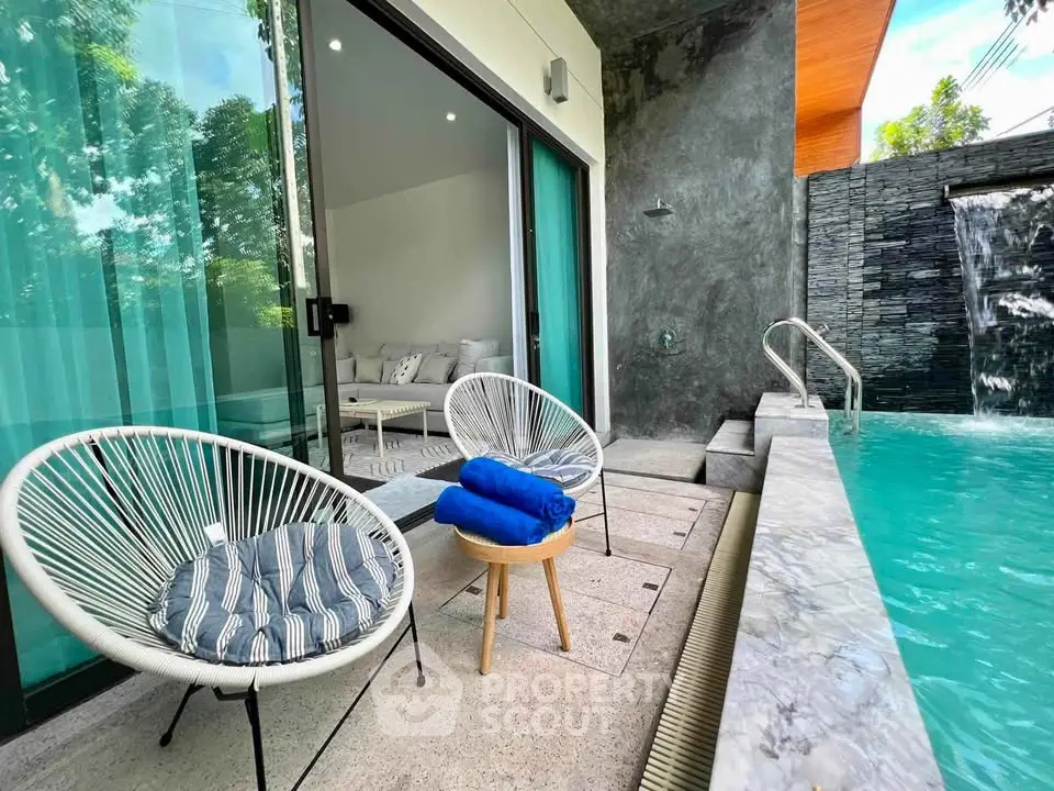 Luxurious poolside patio with modern seating and waterfall feature, perfect for relaxation and entertaining.