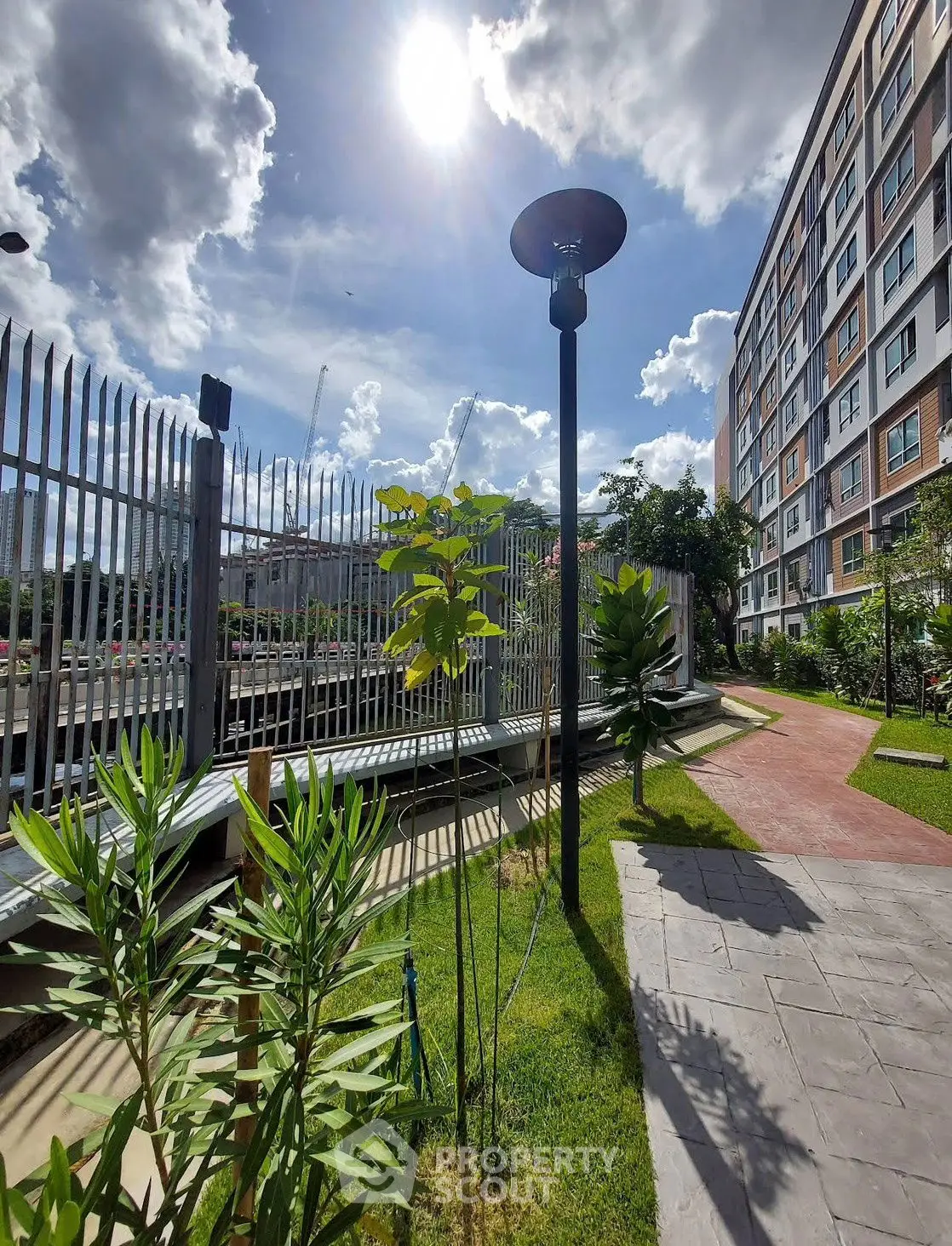 Modern apartment building with landscaped garden under a bright sunny sky.