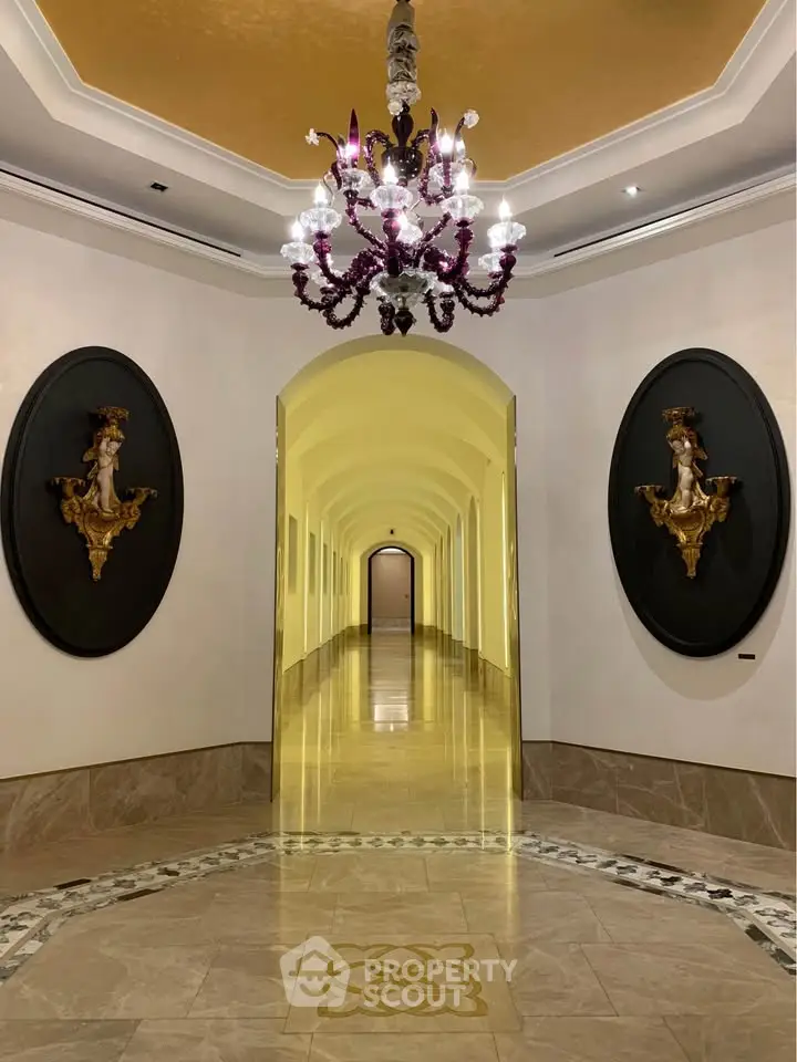 Luxurious hallway with elegant chandelier and ornate wall decor in upscale building.