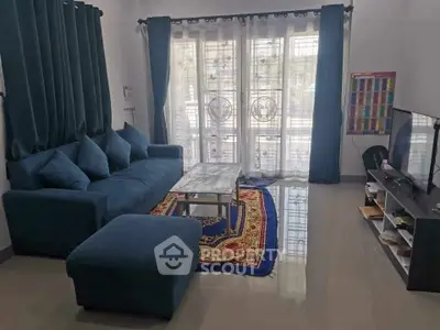Cozy living room with blue sofa, elegant curtains, and modern TV setup.