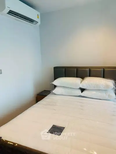 Modern bedroom with air conditioning and neatly arranged pillows on a comfortable bed.