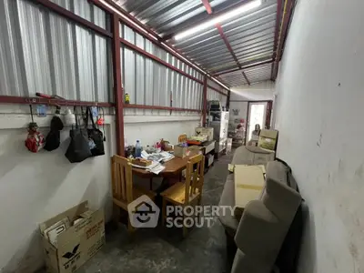 Industrial-style storage room with metal roof and basic furnishings.