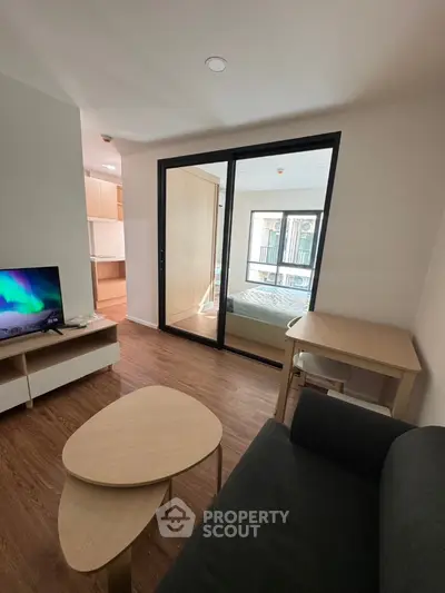 Modern living room with wooden flooring and glass partition to bedroom
