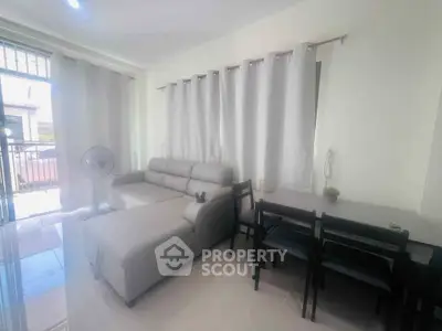 Modern living room with sleek sofa and dining area, featuring large windows and elegant curtains.