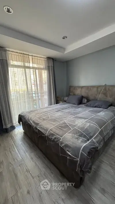 Spacious bedroom with modern decor and large window for natural light