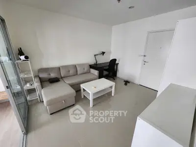 Modern living room with cozy sofa, sleek desk, and minimalist decor in a bright apartment.