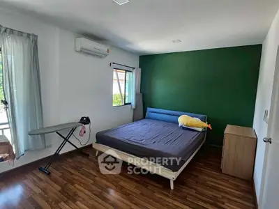 Spacious bedroom with modern decor and hardwood flooring, featuring a large window and air conditioning.