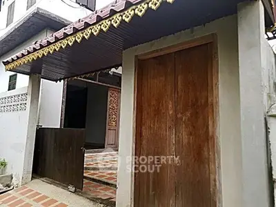 Charming traditional entrance with wooden doors and decorative roof accents.