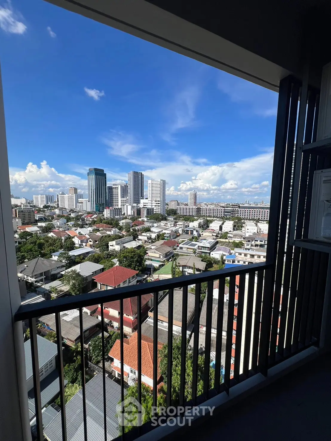 Stunning cityscape view from a high-rise balcony with clear blue skies and modern urban skyline.