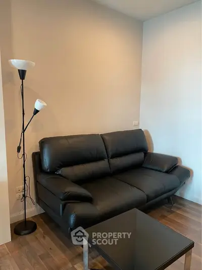Modern living room with sleek black leather sofa and stylish floor lamp.