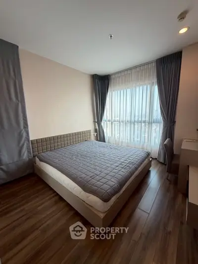 Modern bedroom with large window and stylish decor in a high-rise apartment.