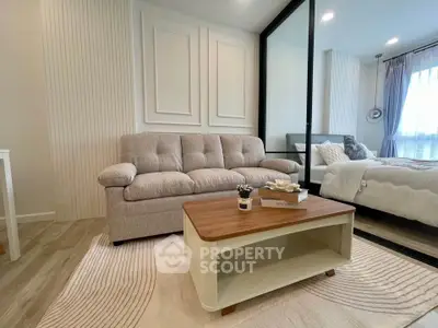 Modern living room with cozy sofa and elegant bedroom in open layout apartment.