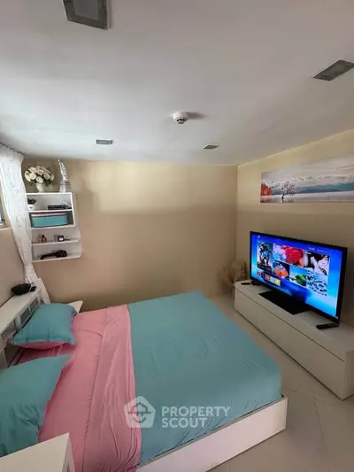 Cozy bedroom with modern decor and large TV, perfect for relaxation.