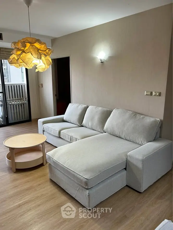 Modern living room with stylish sofa and unique pendant light, perfect for relaxation and comfort.