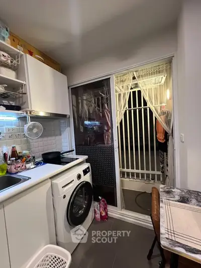 Cozy kitchen with washing machine and balcony access, perfect for modern living.