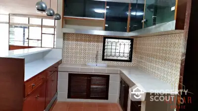 Spacious kitchen with wooden cabinets and tiled countertops, featuring a built-in oven and ample natural light.