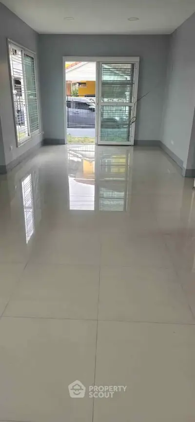 Spacious empty living room with large windows and glossy tiled floor