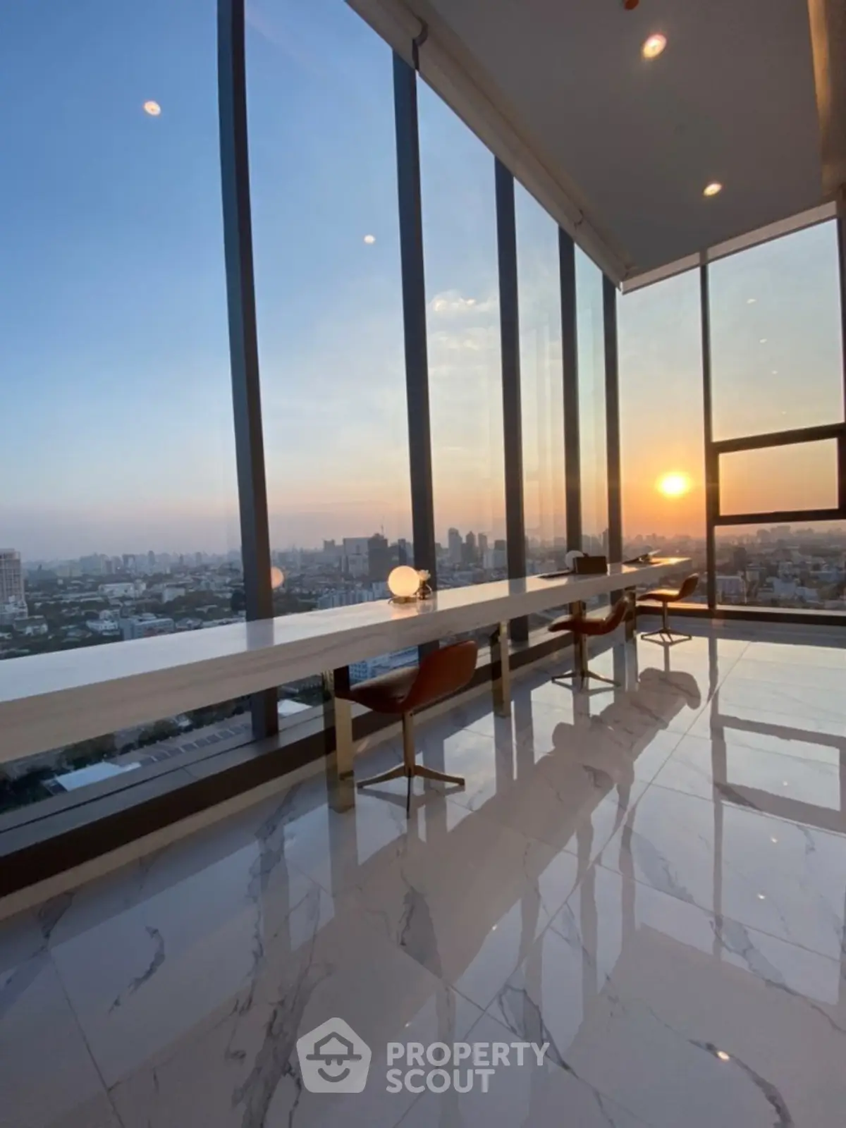 Luxurious high-rise apartment with stunning sunset city view and elegant marble flooring.
