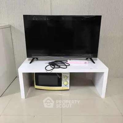 Modern living room setup with sleek TV and microwave on a minimalist white stand.