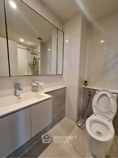 Modern bathroom with sleek fixtures and large mirror in contemporary apartment.
