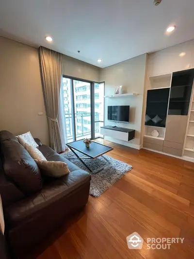 Modern living room with sleek furniture and large windows offering city views.