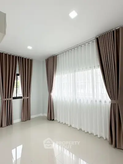 Spacious empty room with elegant curtains and natural light, perfect for customization.