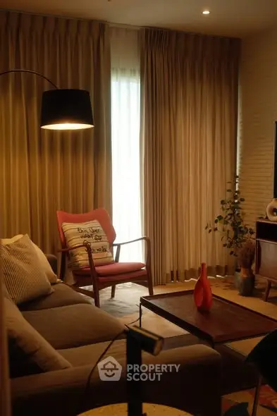 Cozy living room with modern decor and warm lighting, featuring a stylish armchair and elegant curtains.