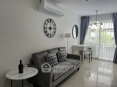 Modern living room with stylish decor and natural light, featuring a cozy sofa and elegant wall clock.